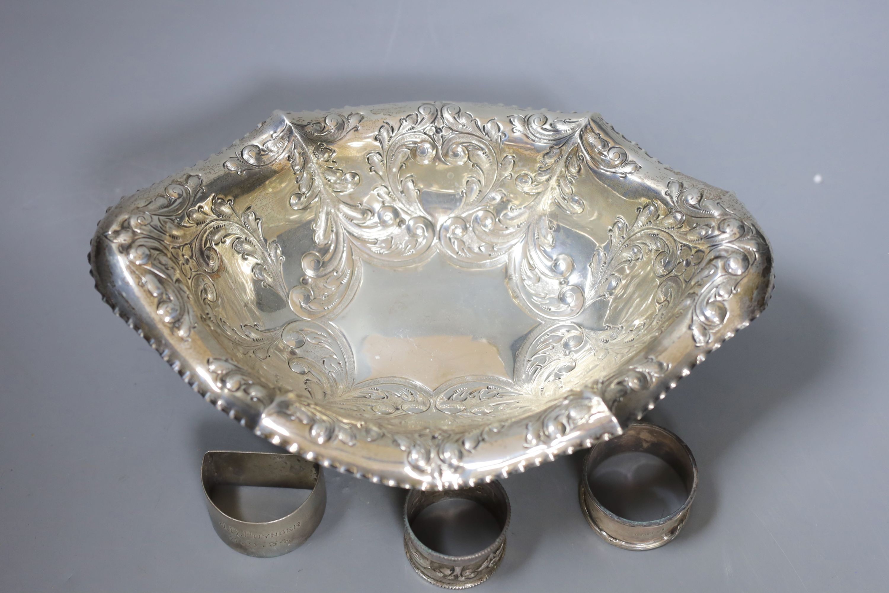 An Edwardian repousse silver pedestal bowl, Sheffield, 1901, 28.5cm and three silver napkin rings, 12.5oz.